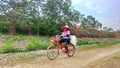 Serang, Indonesia, Friday, October 20 2023 a woman rides a bicycle while carrying a sack on the back and wearing a hat