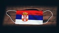 Serbia National Flag at medical, surgical, protection mask on black wooden background. Coronavirus CovidÃ¢â¬â19, Prevent infection,