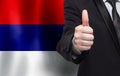 Serbian concept. Businessman showing thumb up on the background of flag of Serbia