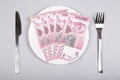 Serbian dinar money on a white plate with fork and knife on a gray background, top view, flat lay. Royalty Free Stock Photo