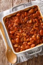 Serbian food: prebranac baked beans with onion close-up in baking dish. Vertical top view from above Royalty Free Stock Photo