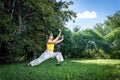 Serene adult woman doing qigong exercise in the park.