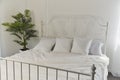 Serene and airy bedroom interior with fresh greenery accent. Modern minimalist bedroom with white linens. Royalty Free Stock Photo