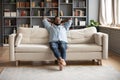 Serene barefoot african man resting on sofa hands behind head