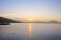 Serene bay on Greek coast with the sun setting behind distant mountains