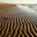 A serene beach landscape features intricately patterned sand ripples leading toward the ocean. The Royalty Free Stock Photo