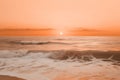 A serene beach at sunset with gentle waves under a soft peach fuzz color sky. Modern trendy tone hue shade