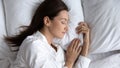 Serene beautiful woman sleeping on soft pillow close up