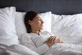 Serene beautiful woman sleeping under warm blanket in comfortable bed