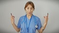 A serene caucasian nurse in blue scrubs performs a meditation pose against a white background Royalty Free Stock Photo
