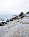 Serene coastal scene featuring a balanced stone stack on a rocky beach under a cloudy sky. Royalty Free Stock Photo