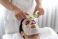 Man customer indulges in rejuvenating with cucumber facial care. Quiescent