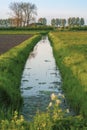 Serene Dutch polder farmland with a water-filled canal running through the middle of the farm fields in Holland in the Netherlands Royalty Free Stock Photo
