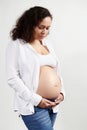 Serene ethnic pregnant woman 30s old, expecting a baby, touching belly on white background. Pregnancy 6 month. 24 weeks.