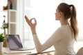 Serene healthy calm woman sitting at desk doing yoga exercises