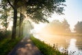 Misty Sunrise on a Tranquil Country Road by the River Royalty Free Stock Photo