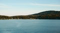 Serene lake with forested hill under blue sky Royalty Free Stock Photo