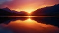 A serene lake mirrors the silhouette of a mountain range as the sun sets behind them in a blaze of vibrant colors