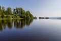 The serene Lake Snasa in Steinkjer, Norway, mirrors a wooden Kvam Church, nestled among dense trees along its tranquil shores