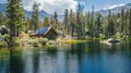 A serene lake surrounded by trees and mountains with a small offgrid cabin in the background. Solar panels are visibly Royalty Free Stock Photo