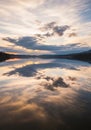 A serene lakescape reflects the evening sky, capturing softly diffused clouds in a Royalty Free Stock Photo