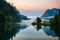 A serene lakeside scene at dawn with mist rising from the water and a tranquil forest in the background