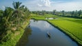 A serene landscape featuring a river, lush rice fields, and a small boat under a blue sky Royalty Free Stock Photo