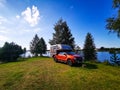 Serene landscape of a red pickup caping truck on the lakeside on a sunny day in Finland