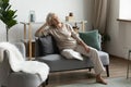 Serene mature 60s woman relaxing in modern comfortable living room Royalty Free Stock Photo
