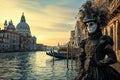 A serene morning at the Venetian Carnival, a lone figure in a traditional mask and costume, standing by the edge of a canal with Royalty Free Stock Photo