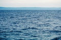 Serene nautical landscape with blue sea water waves, mountains on horizon and light sky