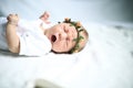 Serene newborn baby on a bed yawning