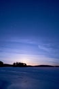 Serene nighttime winter landscape with a frozen lake and blue sky Royalty Free Stock Photo