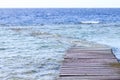 Serene old wooden dock extending into tranquil blue ocean water Royalty Free Stock Photo