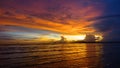 Serene orange lit sunset shining on tranquil ocean, beaches and lonely boats.