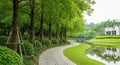 Serene Park Pathway Lined with Trees and Water Feature with Building in Background walkway Royalty Free Stock Photo