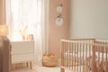 Serene pastel nursery room with a wooden crib, decorative vases, wall-mounted plant decor, and soft lighting