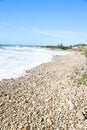 Serene pebbled beach with crystal-clear turquoise waters and a vibrant blue sky