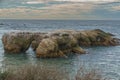 A serene rocky beach at sunset, with dramatic clouds casting a captivating display of colors across the sky