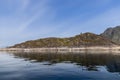 A serene Scandinavian fjord with a lone lighthouse atop a moss-covered rocky island