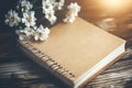 Soft Light on Blank Notebook with White Flowers on Wooden Table Background Royalty Free Stock Photo