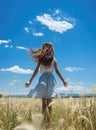 back view of a girl standing in a flower grass field with open arms freedom and fresh air blue sky mountain view