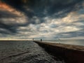 serene seaside sunset with dramatic clouds, seagulls, pier, and person on the pier