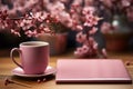 Serene setup, notebook, blooms, and coffee adorn pink table in harmonious arrangement