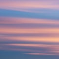A serene sky with horizontal streaks of soft pink and blue clouds. The light creates a Royalty Free Stock Photo