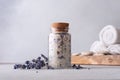 A serene spa setting with a glass jar of aromatic lavender salt sealed with a cork, surrounded by scattered lavender flowers, Royalty Free Stock Photo