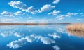 A serene spring lake reflecting the clear blue sky and fluffy white clouds Royalty Free Stock Photo