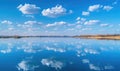 A serene spring lake reflecting the clear blue sky and fluffy white clouds Royalty Free Stock Photo