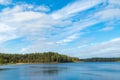 A serene summer landscape. Forest lake on the background of a blue sky with clouds. slender trees on the far shore Royalty Free Stock Photo