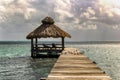 View of beach hut at the end of pier on green ocean tropical waters. Royalty Free Stock Photo